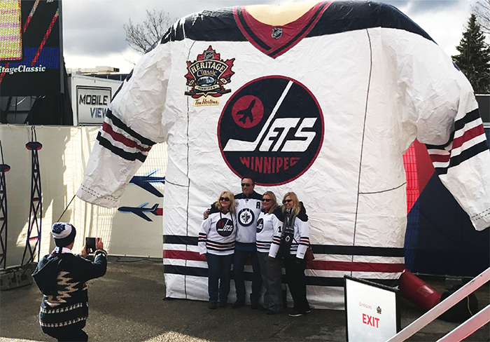 Fans pose in front of a giant Winnipeg Jets jersey at the NHL Heritage Classic 2016 Spectator Plaza in Winnipeg.